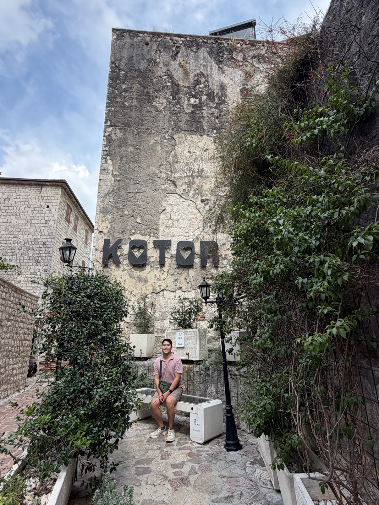 Kevin seated beneath the Kotor sign in the old town of Kotor, Montenegro