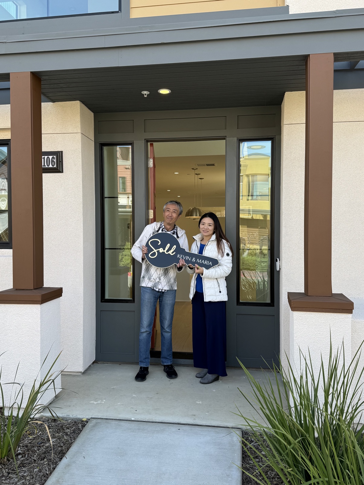Henry C. and his partner holding a sold sign in front of their townhouse