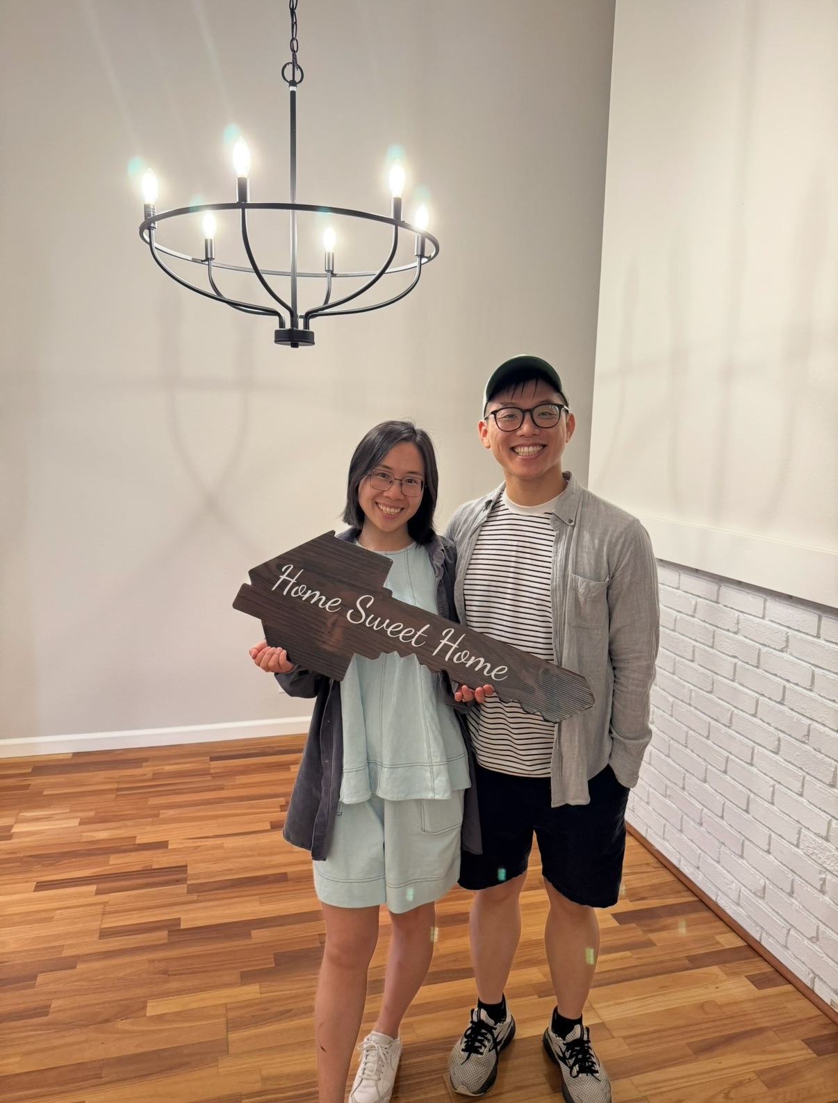 Jimmy P. and his partner holding a Home Sweet Home sign inside their new home